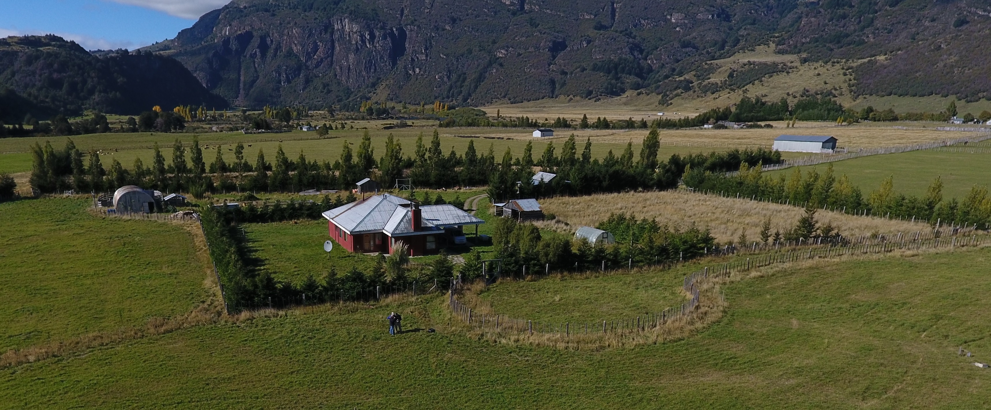 Vista aérea con drone del Fundo La Pampita en 2017 — casa roja, galpones, cortinas y potreros, Manihuales, Aysén